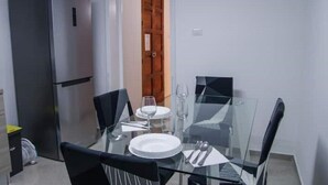 A dining area with a glass table, black chairs, and a stainless steel refrigerator. - 2 Bedroom Apartment in Cutrofiano (Cutrofiano)