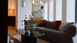 A modern living room with a grey sofa, a glass coffee table, and a decorative vase with dried flowers.