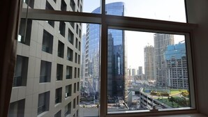 A view through a window of a modern building with a grid-like facade and a glass skyscraper in the background. - Cozy 1BR Buisness bay Damac Cour Jardin (Dubai)