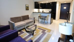 A modern living room with a sofa, a glass coffee table, and a dining area with a table and chairs. - Cozy 1BR Buisness bay Damac Cour Jardin (Dubai)
