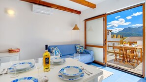 A dining area with a table set for two, a bottle of Parmalat wine, and a view of a mountainous landscape through a glass door. - Apartment Bellavista Viddalba (Sardegna)