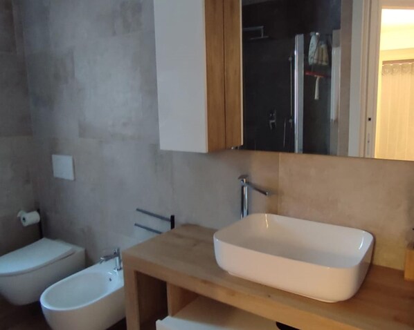 A bathroom with a beige vanity, a white sink, and a bidet. - Elyana s Home in Vezza d Oglio (Vezza d'Oglio)
