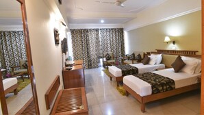 A hotel room with two beds, a ceiling fan, a TV, a desk, and a mirror. - Ganga Resort (Narendranagar)