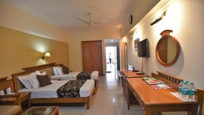 A hotel room with two beds, a desk, a TV, and a mirror. - Ganga Resort (Narendranagar)