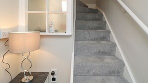 Un escalier avec une rampe, une fenêtre à vitre dépolie et une lampe sur une table.