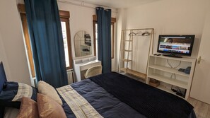 Een hotelkamer met een bed, een bureau met stoel, een televisie en een kledingkast.