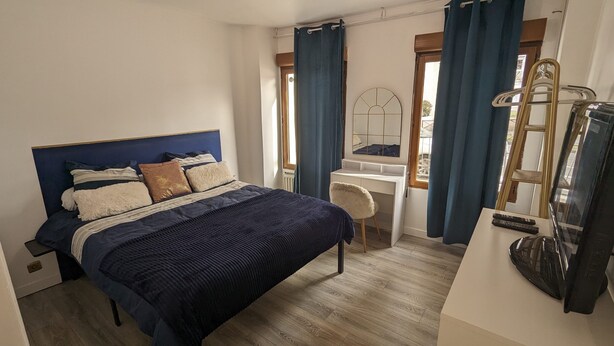 Un dormitorio con una cama, un escritorio, una silla y un espejo.