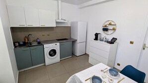 Una cocina compacta con lavadora, refrigerador y cafetera.