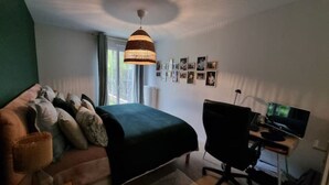 A bedroom with a bed, a desk with a computer, a chair, and a hanging lamp. - JO bel Appart Proche Versailles (Louveciennes)