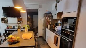 A narrow kitchen with a wooden island, white cabinets, and a built-in oven. - JO bel Appart Proche Versailles (Louveciennes)