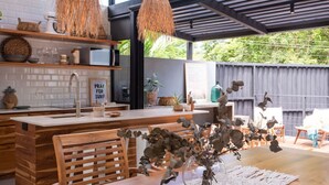 A modern kitchen with a wooden island, pendant lights, and a view of the backyard. - Boho Oasis in the heart of town (Tamarindo)