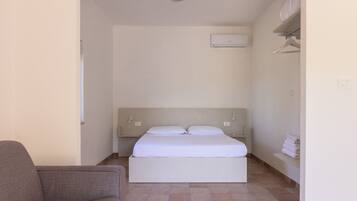 Una camera da letto con un letto, un comodino, un appendiabiti a parete e un climatizzatore.