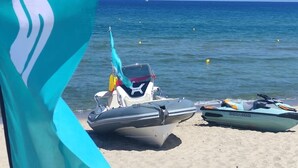 A beach with two boats and a flag. - Q Resort (Sorso)