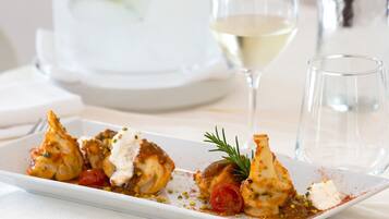 Une assiette blanche contenant de la nourriture, un verre à vin et une bouteille d’eau sont posés sur une table.
