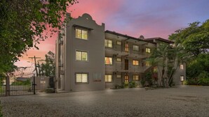 A multi-story building with a courtyard, surrounded by trees and a gravel ground. - Charming  1bedroom 5 mins to beach (Tamarindo)