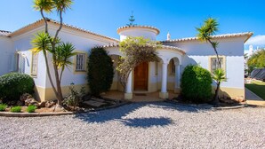 Une maison à deux étages avec une entrée centrale, un porche couvert et une petite tour.