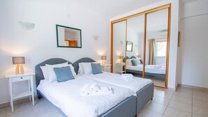 Une chambre d’hôtel avec deux lits, un grand miroir et une armoire.