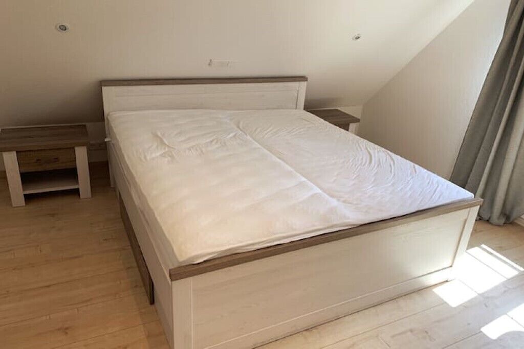 A bedroom with a single bed, a bedside table, and a bench.