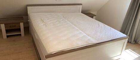A bedroom with a single bed, a bedside table, and a bench.