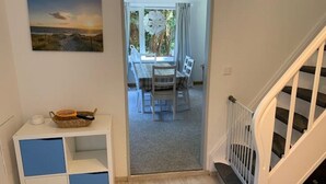 A room with a view of a dining area, a white cabinet with blue doors, and a staircase. - Ferienhaus Muschel mit Garten an der Nordsee (Dornum)