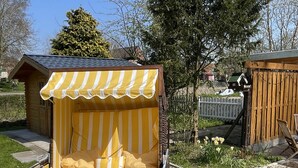 A small wooden structure with a striped awning and a bench. - Ferienhaus Muschel mit Garten an der Nordsee (Dornum)