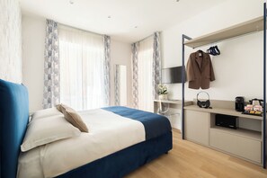 Ein modernes Schlafzimmer mit einem Bett, einem Schreibtisch, einem Fernseher und einem Kleiderständer.