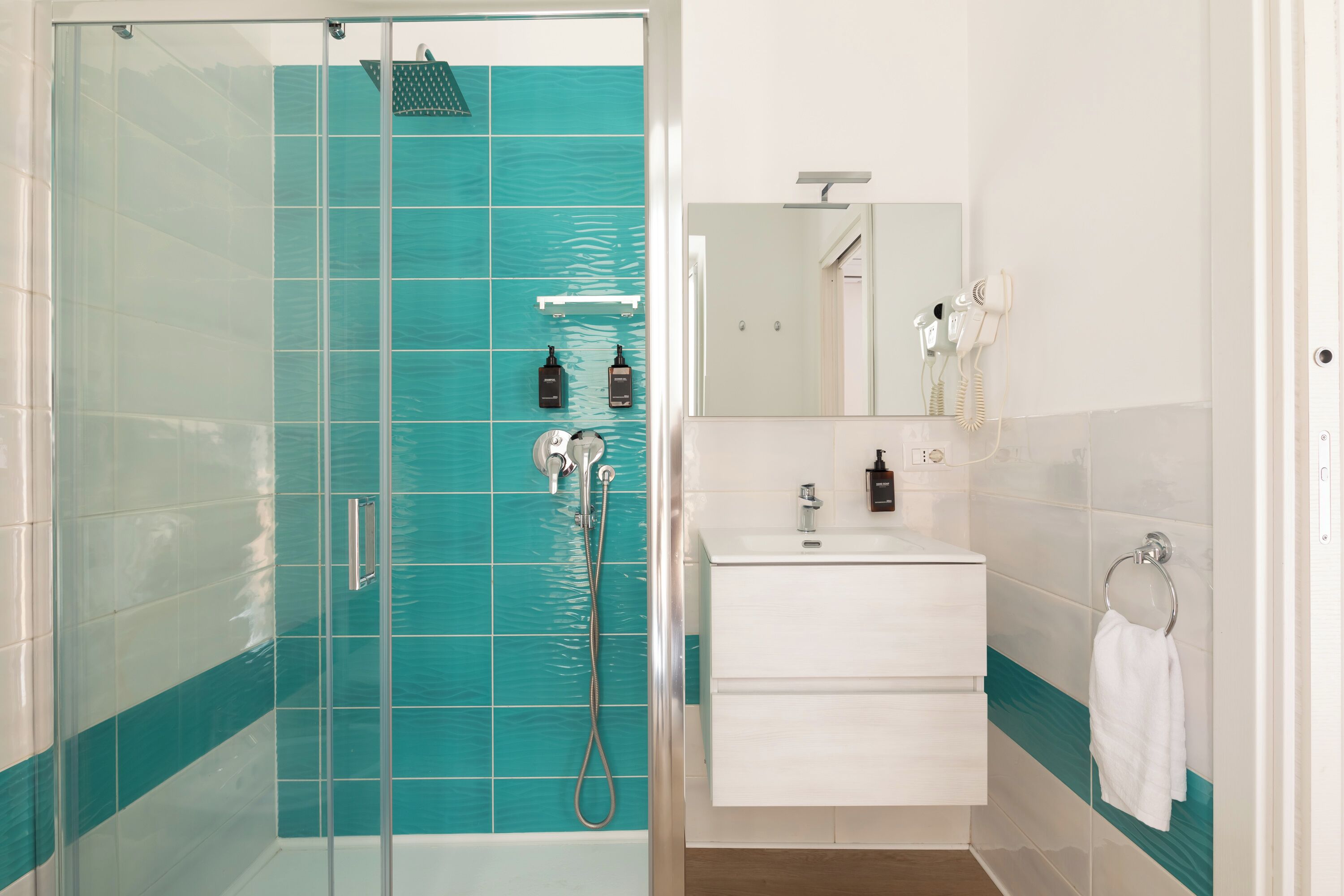 A bathroom with a glass-enclosed shower, a white sink, and a mirror above it.