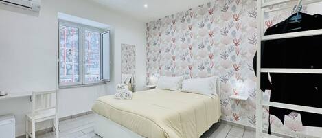 A modern bedroom with a bed, a desk, and a wardrobe.