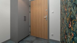 Una habitación con un armario gris, una puerta de madera y un papel tapiz estampado.