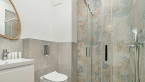 A modern bathroom with a glass-enclosed shower, a white sink, and a toilet.