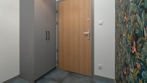 A room with a grey wardrobe, a wooden door, and a patterned wall.
