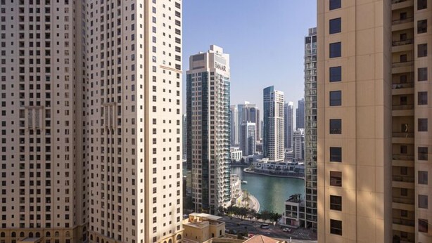 A high-rise building with a pool and a view of a cityscape and water body. - Modern 2BR Oasis with Breathtaking Views (Dubai)