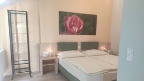 Un dormitorio con cama, mesitas de noche, un cuadro en la pared y suelo de madera.