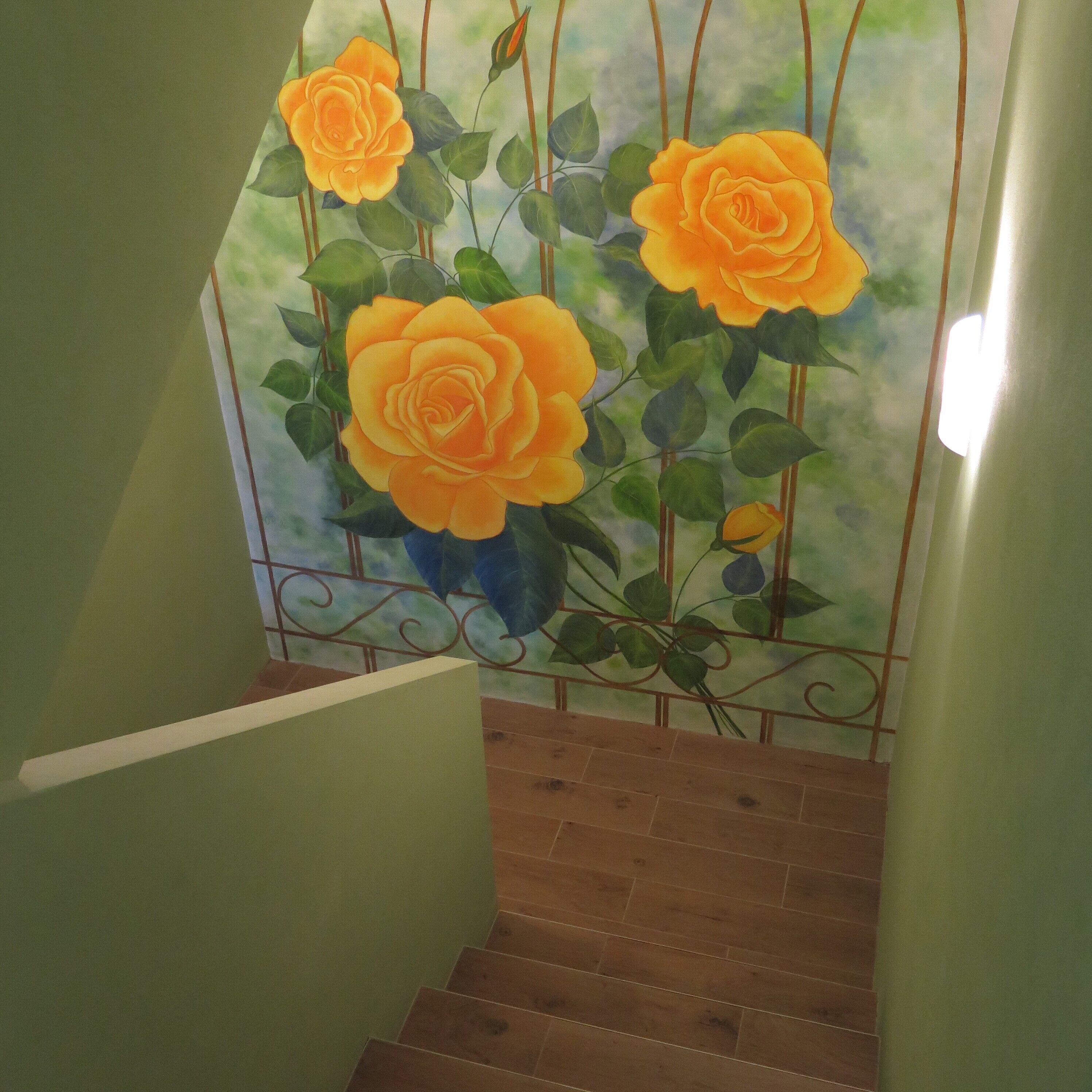 A staircase with a green wall and a mural of orange roses.