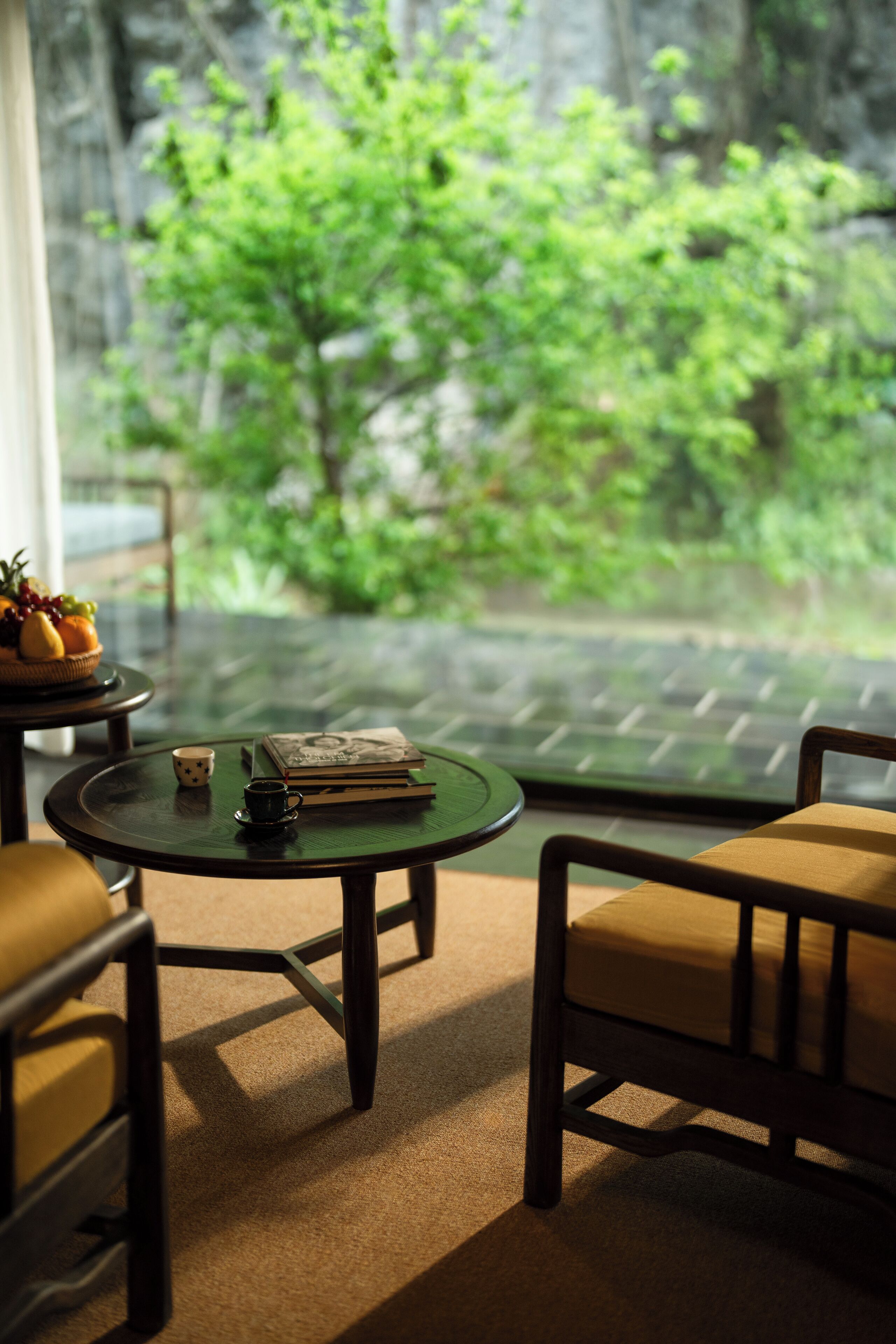 A cozy seating area with a table, chairs, and a view of greenery outside.