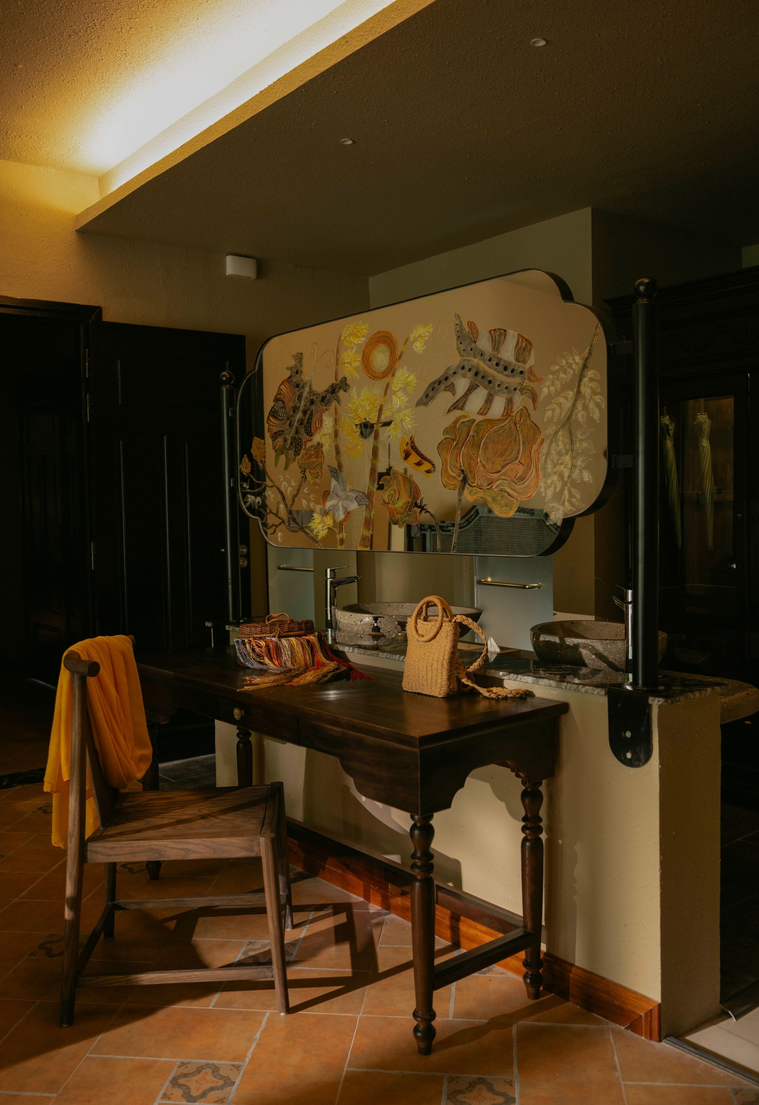 A wooden dining table with a woven basket and a chair with an orange towel.