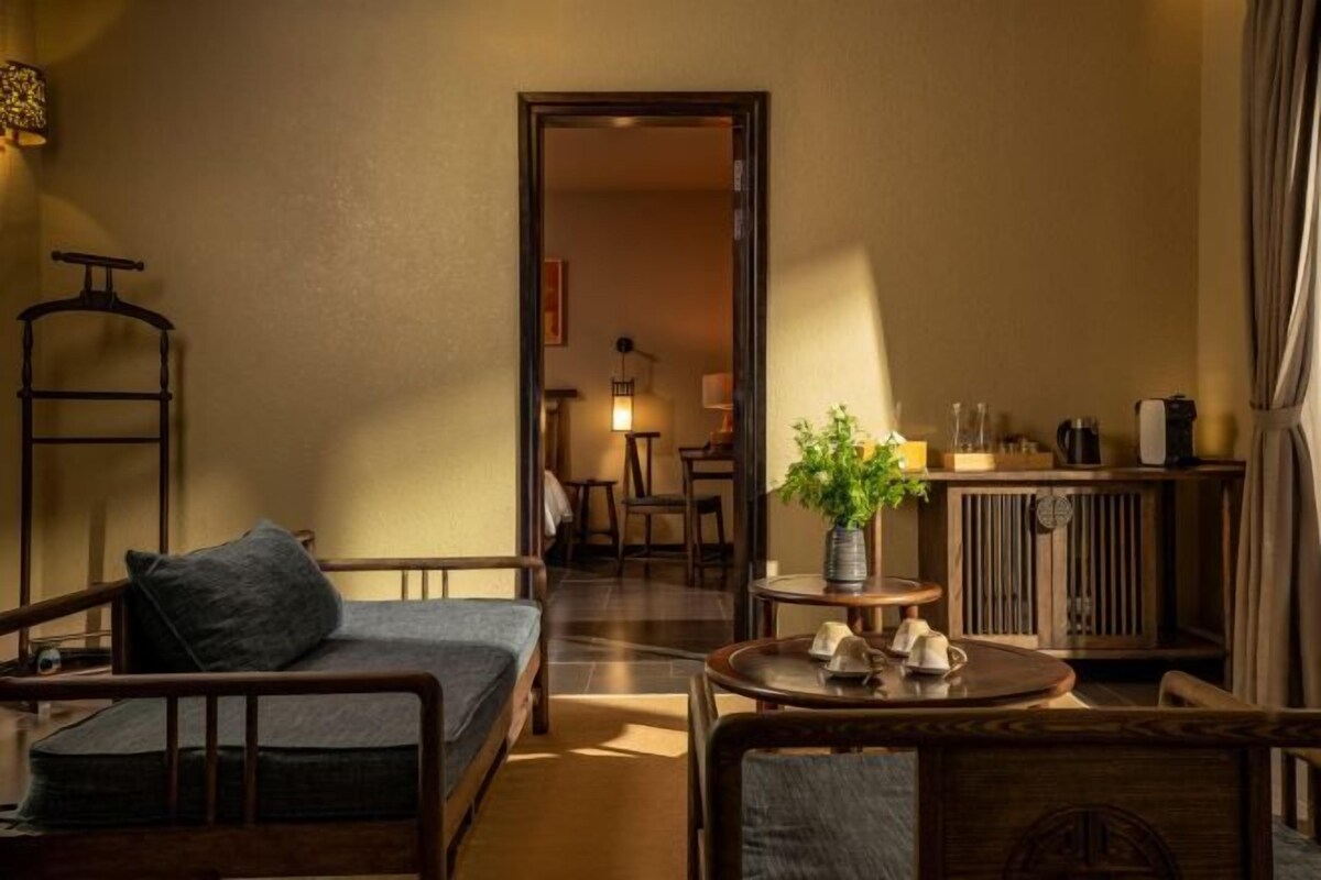 A cozy room with a sofa, a small table with a plant, and a cabinet with various items.