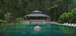 A woman in a swimming pool with a traditional building in the background. - Jiva Hoa Lu Retreat (Nam Hoa Lu)