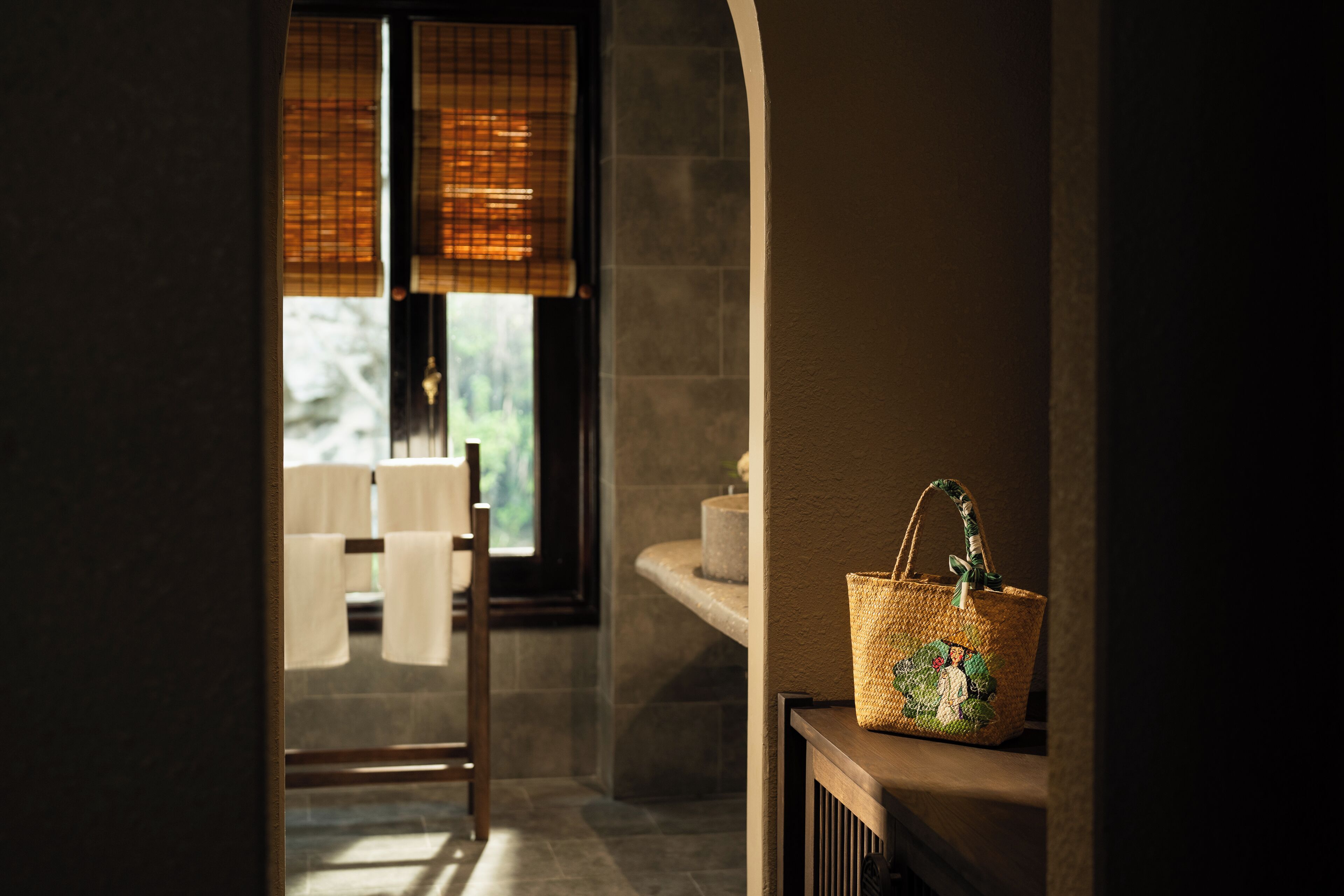 A bathroom with a towel rack, a wicker basket, and a window with blinds.
