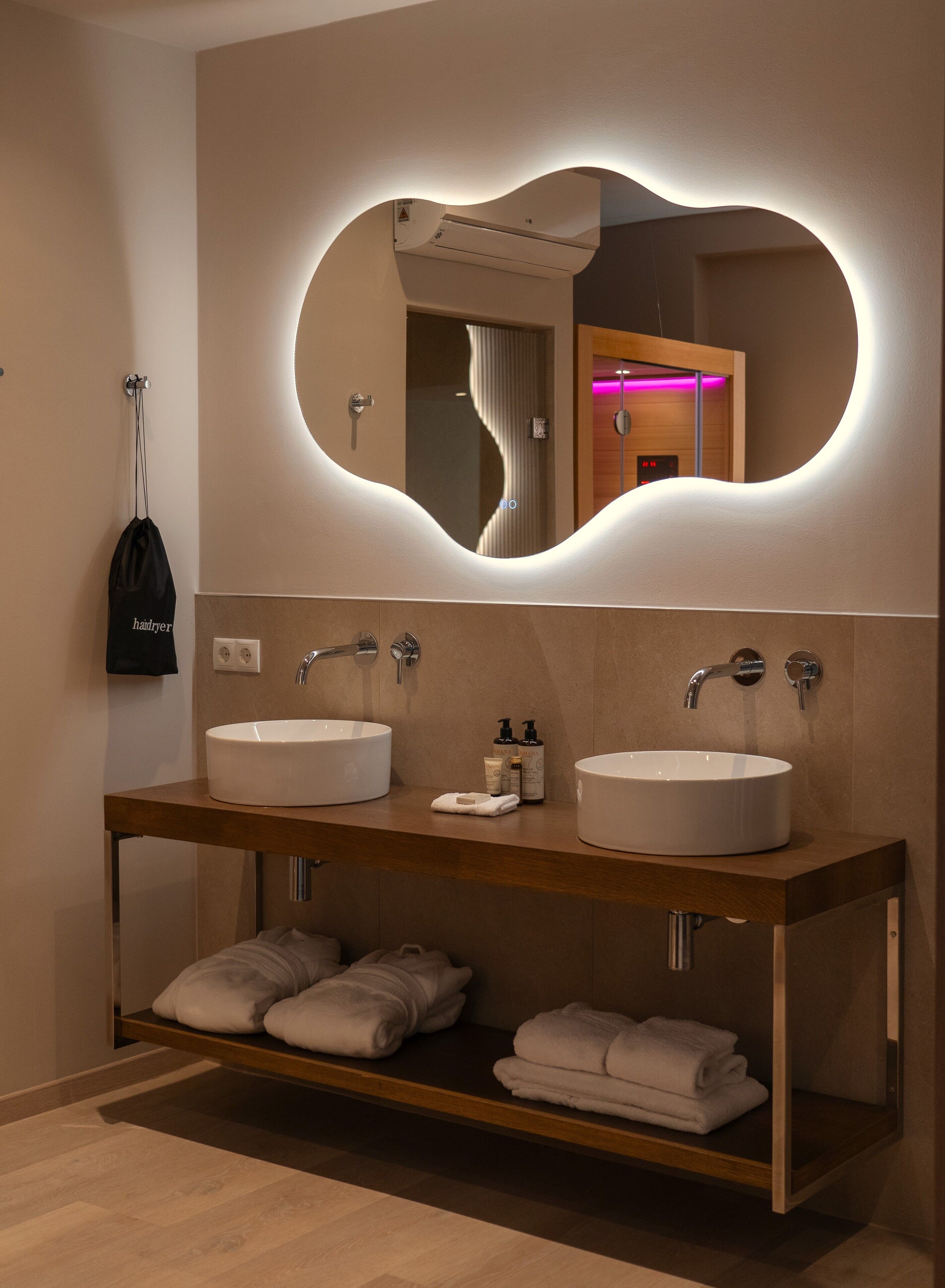A modern bathroom with two sinks, a mirror with a heart-shaped frame, and a towel rack.