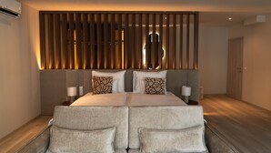 Un dormitorio moderno con una cama grande, dos mesitas de noche con lámparas, un cabecero de madera con listones verticales y suelo de madera.