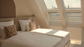 Une chambre à coucher moderne avec un grand lit, des fenêtres de toit et une vue sur le paysage urbain.