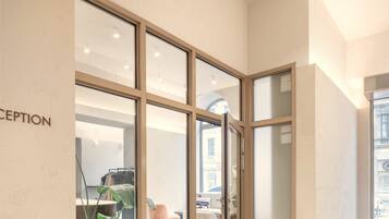 Un área de recepción con puerta de cristal, mostrador de recepción y una planta en maceta.