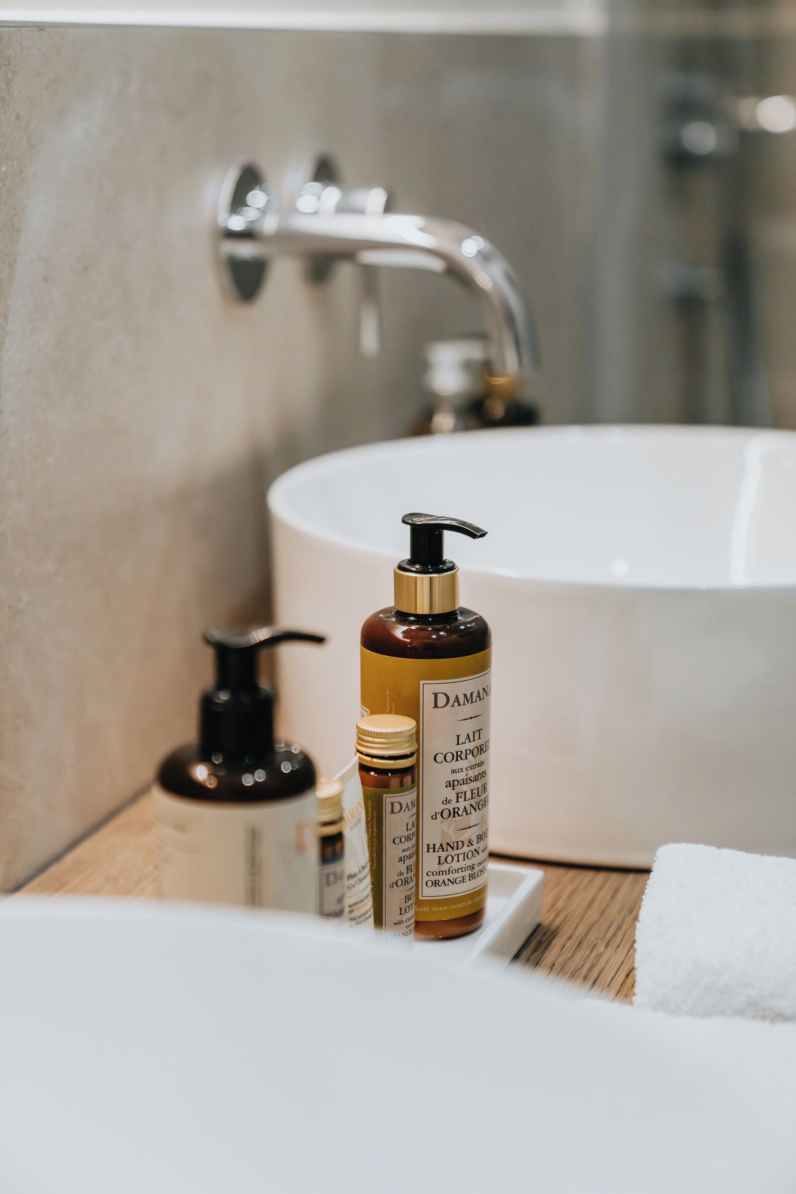 A bathroom with a bathtub, a white sink, and toiletries including a bottle of lotion and a soap dispenser.