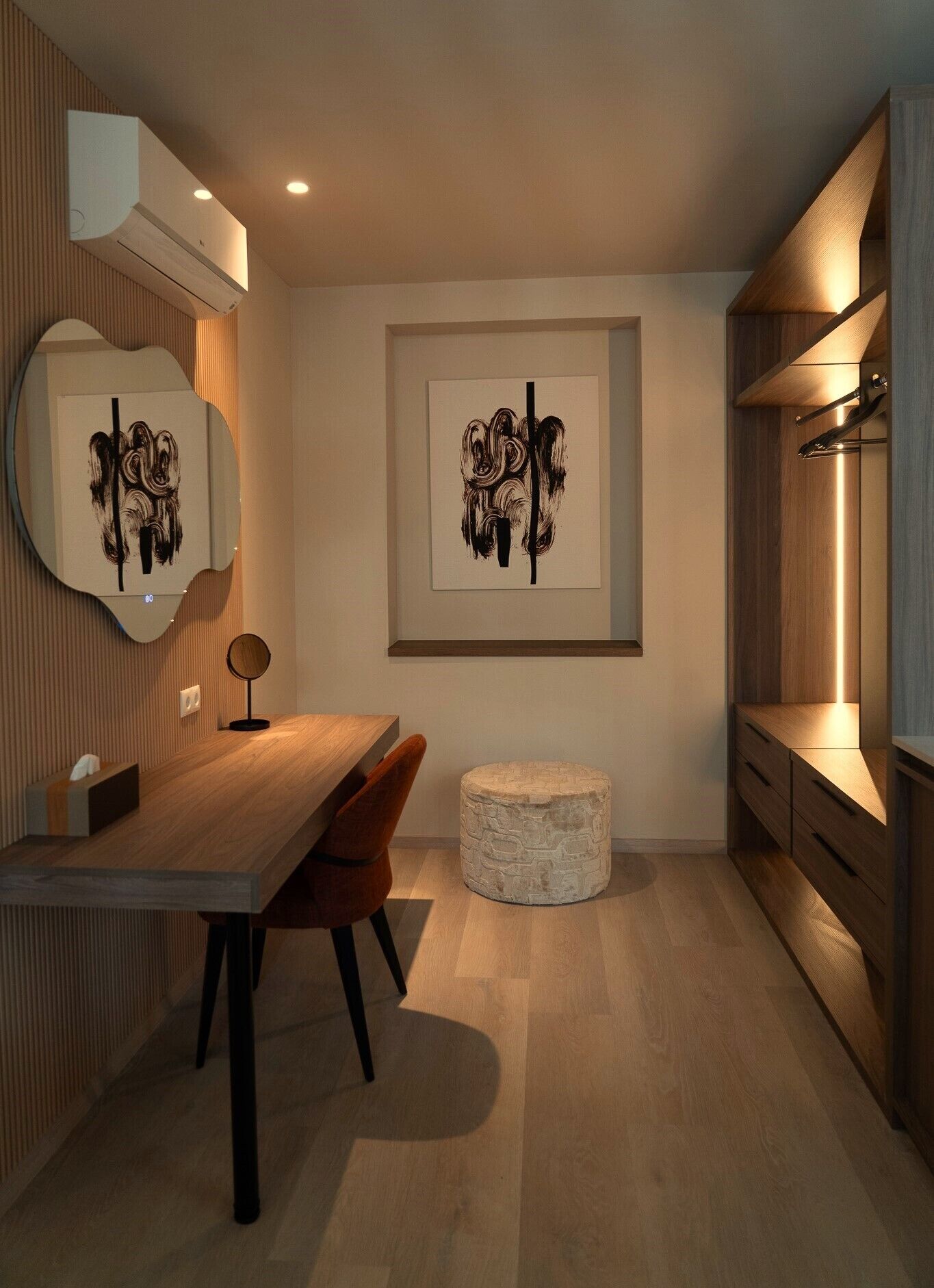 Una cocina moderna con una mesa de comedor de madera, dos sillas, un otomano de piedra redondo y obras de arte en las paredes.