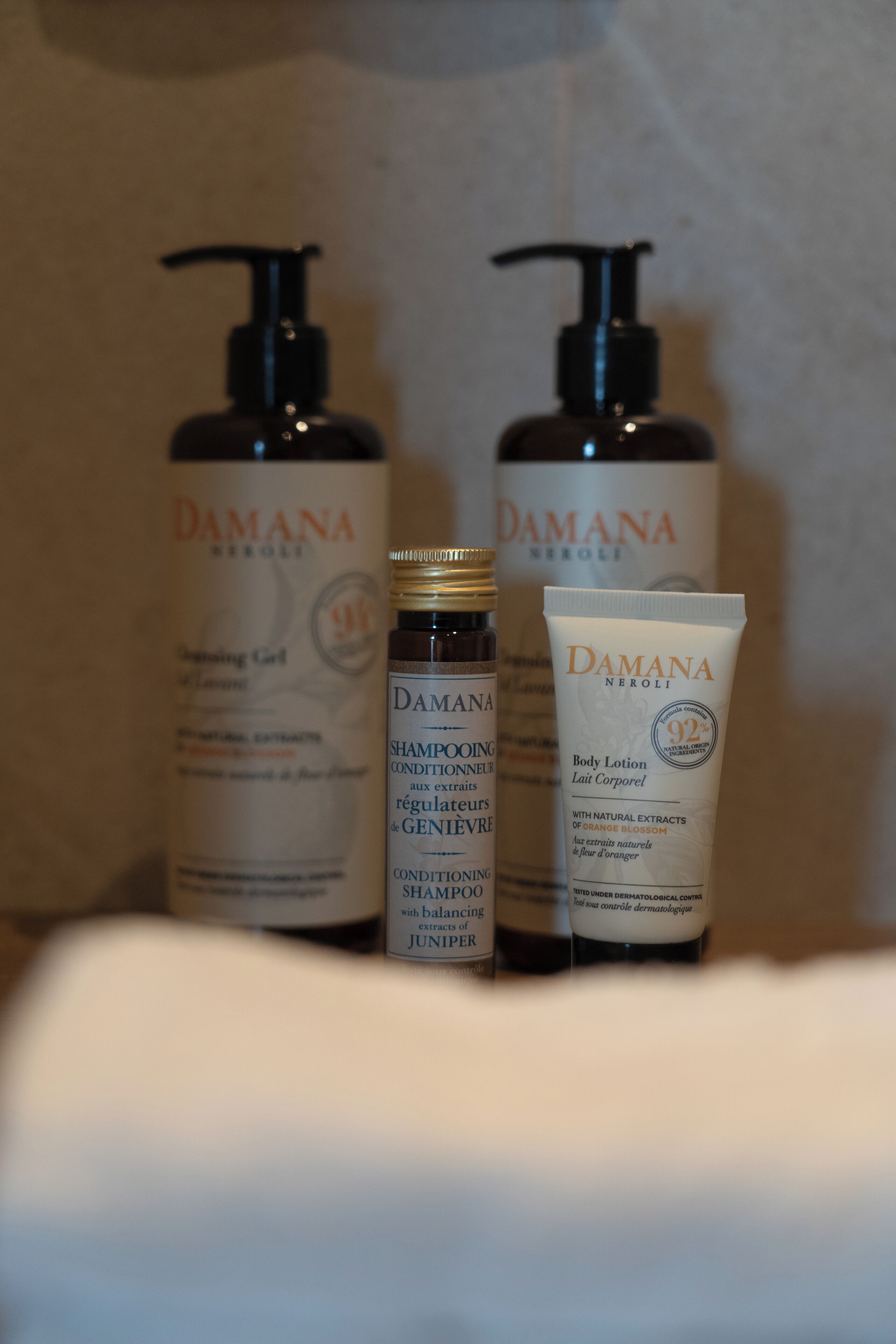 Three bottles of Damana body care products on a shelf.