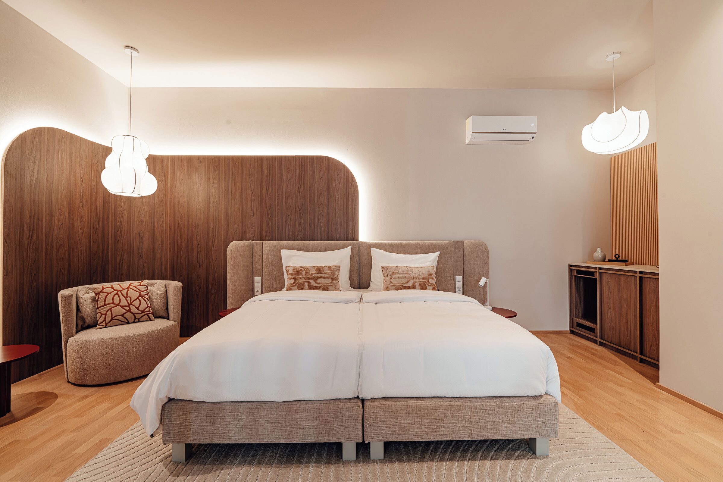 Een moderne slaapkamer met een groot bed, een stoel en een houten kast.
