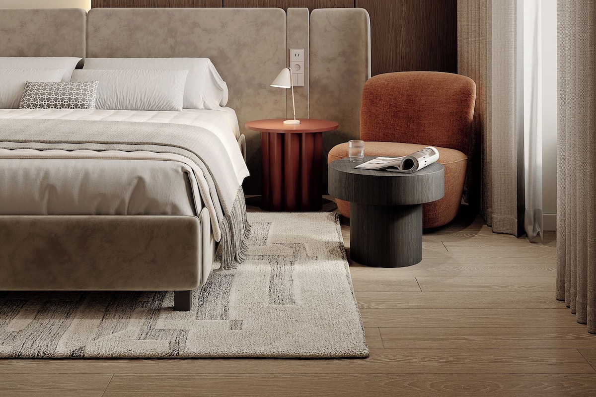 A modern bedroom with a large bed, a side table, a chair, and a round table.