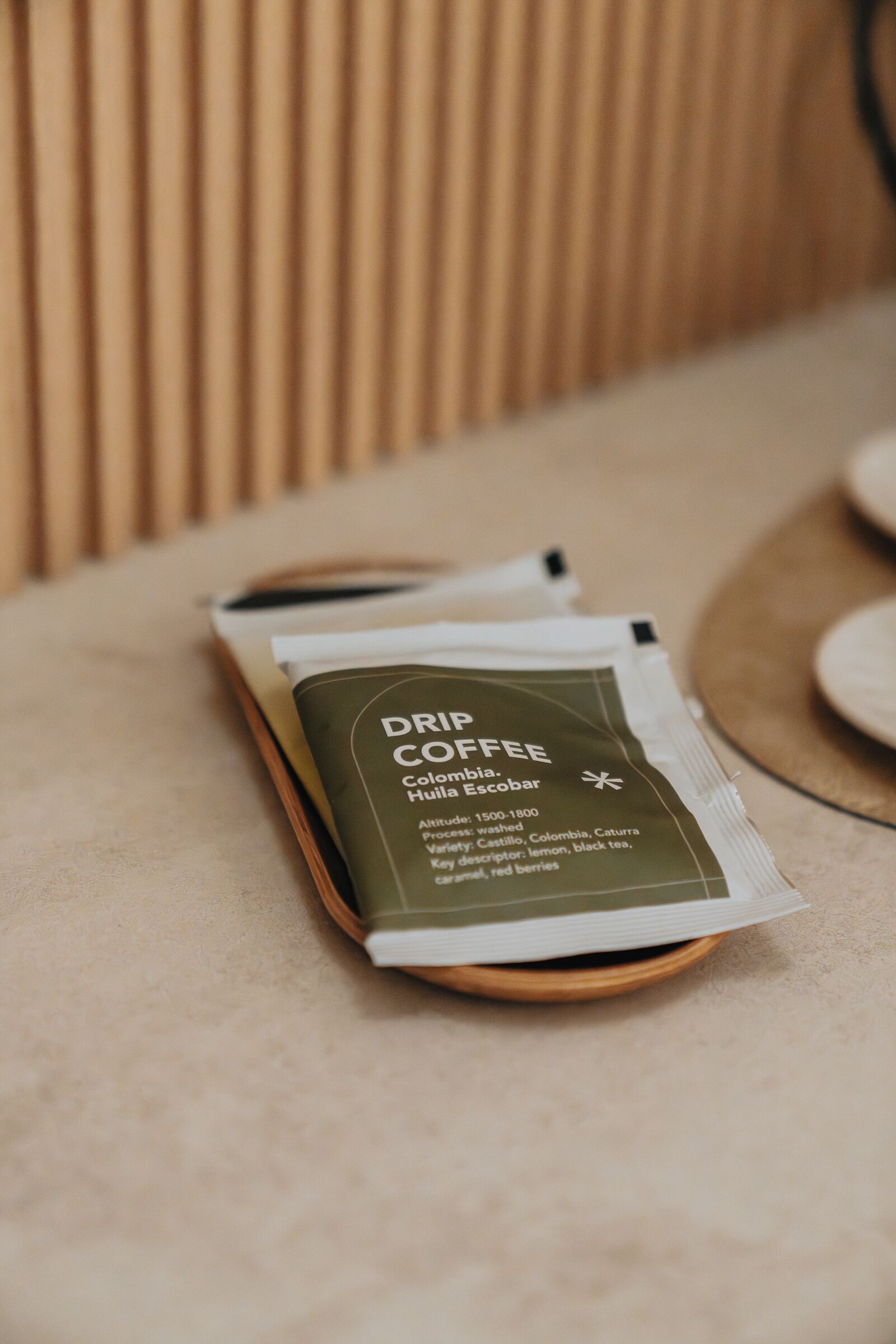 Un paquete de café de filtro con la etiqueta 'Colombia, Huila Escobar' sobre una bandeja de madera.