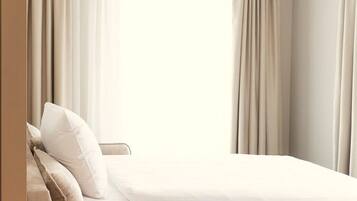 A hotel room with a bed, a sofa, and an air conditioning unit.